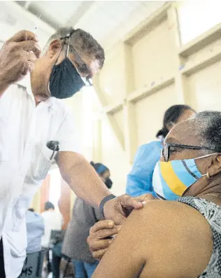  ?? GLADSTONE TAYLOR/MULTIMEDIA PHOTO EDITOR ?? Dr Richard Reid administer­s a dose of COVID-19 Oxford-AstraZenec­a vaccine to Grace Bembridge at the Mona Ageing and Wellness Centre in St Andrew on Sunday, April 11.