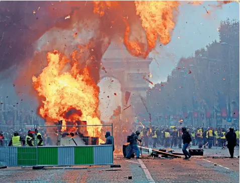  ??  ?? A fire rages as violence breaks out on the Champs-Elysées, where police confronted marchers wearing yellow vests, who were protesting at rising fuel prices and living costs