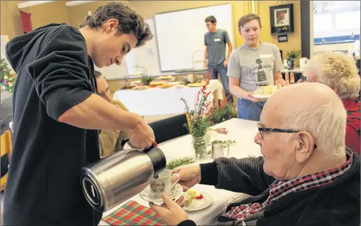  ?? MILLICENT MCKAY/JOURNAL PIONEER ?? Ethan Boyko, left, serves Ralph MacDonald tea, as Michael Stewart, right makes his way around the table with egg sandwiches. Recently the Grade 10 foods students at KRHS invited community members to learn recipes for the Christmas tea.