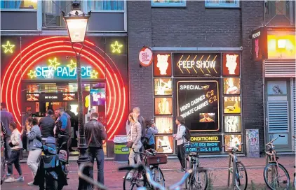  ?? AFP ?? People walk in the red light district of Amsterdam on Wednesday as Dutch brothels reopened after a long coronaviru­s shutdown, with sex workers and clients having to observe new rules to prevent Covid-19 infection.
