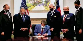  ?? COURTESY ?? Gov. Brian Kemp, flanked by other Georgia legislativ­e leaders, signs election overhaul bills into law last month, an action later criticized by a couple of Atlanta’s corporate titans.