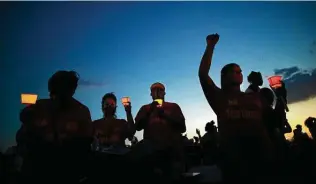  ?? Marie D. De Jesús / Staff file photo ?? Mourners hold candles during a vigil honoring George Floyd last June at the Jack Yates High School football field. A sweeping police reform bill in the Legislatur­e is named in Floyd’s honor.