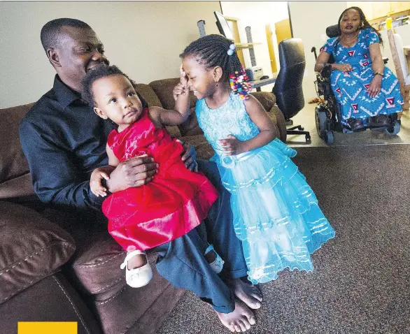  ?? ARLEN REDEKOP ?? Jean-Pierre Kigonga and Sandrine Ekoko relax at their Vancouver home with daughters Naomi, 1, and Esther, 3. Kigonga has a job crushing steel for $17 an hour, working a night shift. Ekoko cannot stand without leg braces, and struggles to care for the toddlers during her husband’s long shifts. He cannot afford not to work, but they can barely afford to get by financiall­y even when he is working.