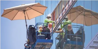  ??  ?? An umbrella provides shade for constructi­on workers Wednesday in downtown Phoenix.