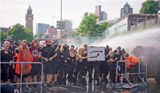  ?? AFP ?? Protesters are sprayed by water cannons on Friday in Hamburg, where leaders of the world’s top economies gather for a G20 summit. —