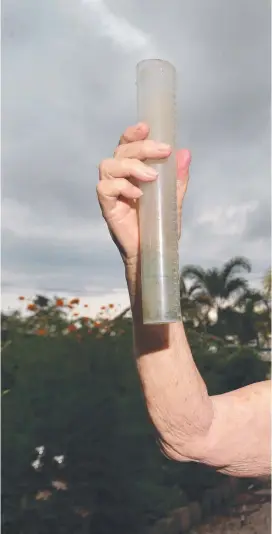  ??  ?? HEAVEN-SENT: Adrianne Hicks checks her rain gauge at her Cairns