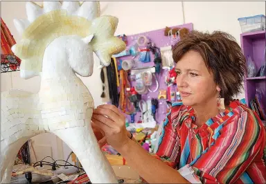  ?? Janelle Jessen/Herald-Leader ?? Artist Amy Haid places hand-cut pieces of glass on an abstract pony sculpture at her new studio in downtown Siloam Springs. The mosaic sculpture already has more than 2,000 pieces of glass.