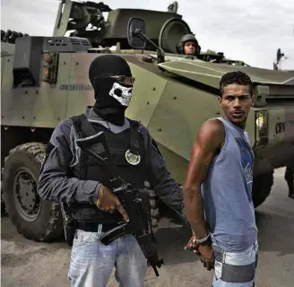  ?? Leo Correa/Associated Press ?? Agente detém homem durante operação na comunidade Kelson’s, na zona norte do Rio