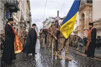  ?? PETROS GIANNAKOUR­IS AP ?? Soldiers carry the coffin of soldier Yurii Bulharu during a funeral ceremony outside the Holy Apostles Peter and Paul Church in Lviv, Ukraine, on Saturday. Bulharu died on Feb. 17 in eastern Ukraine.