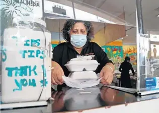  ?? SUSAN STOCKER/SOUTH FLORIDA SUN SENTINEL ?? Catherine Malcolm, owner of the Jerk Machine, serves up a to-go order at her restaurant Thursday in Lauderhill. The restaurant has resorted to a GoFundMe campaign to stay afloat.