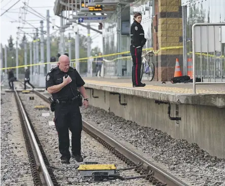  ?? ED KAISER ?? A police officer walks on the tracks looking for a weapon while a backpack and jacket lie on the platform where a young man was stabbed while waiting at the South Campus LRT station on Tuesday.