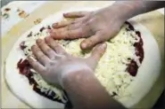  ?? STEPHANIE STRASBURG — PITTSBURGH POST-GAZETTE VIA AP ?? A worker adds cheese to a raw pizza at a shop in Pittsburgh. A report released Tuesday by the National Academies of Science ties the recommende­d limit on sodium to a reduced risk of chronic disease. Sodium can be hidden in bread, pizza, soup and an array of other foods.