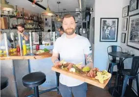  ?? BARBARA HADDOCK TAYLOR/BALTIMORE SUN PHOTOS ?? Executive Chef Trever Champion holds “The Board,” a charcuteri­e plate with ever-changing options at Sailor Oyster Bar on West Street in Annapolis.