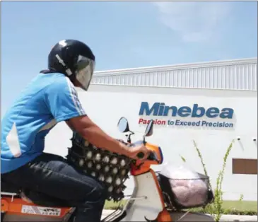  ?? HONG MENEA ?? A motorist passes the Minebea factory at the Phnom Penh Special Economic Zone in 2013.