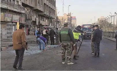  ?? AP PHOTOS ?? DISASTER AREA: Iraqi security forces gather at the scene of a double suicide attack in downtown Baghdad yesterday. Officials said at least 27 people were killed and more than 80 injured.