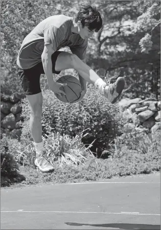  ?? DANA JENSEN/THE DAY ?? Jack Woodruff switches hands holding the ball while in midair, just one one of several moves before taking a shot at the basket while demonstrat­ing one of his basketball trick shots on Friday at his home in Ledyard. Please go to theday.com to view a video of Woodruff’s trick shots.