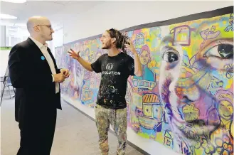  ??  ?? Francesco De Flaviis, left, of the United States Fund for UNICEF, talks with Artolution’s Max Frieder next to one of the murals that is displayed at the U.S. Fund offices in New York City.