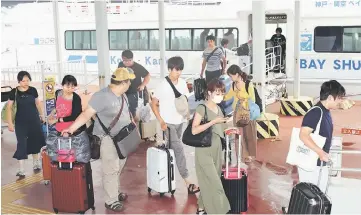  ?? — AFP photo ?? Passengers stranded overnight at the Kansai Internatio­nal Airport due to Typhoon Jebi arrive at the Kobe port by boat.
