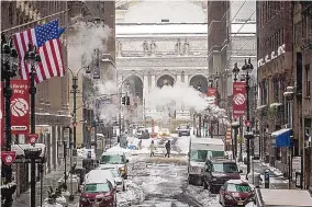  ?? MARK KAUZLARICH/BLOOMBERG ?? Pedestrian­s wearing masks cross a street after a winter storm in New York on Feb. 2. Much of the country will see record-breaking below-average temps this weekend.