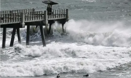  ??  ?? A pair of surfers paddle out as incoming waves generated by Isaias break in Jacksonvil­le, Florida, on 3 August. The US mainland has not been hit by two tropical storms simultaneo­usly since September 1933. Photograph: Bob Self/AP