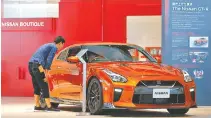  ?? PHOTO BY SHIZUO KAMBAYASHI/AP ?? A visitor looks into a Nissan GT-R on display at Nissan global headquarte­rs in Yokohama, near Tokyo.