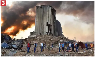  ??  ?? Aftermath: Rescuers search through the twisted metal and ash at the silo