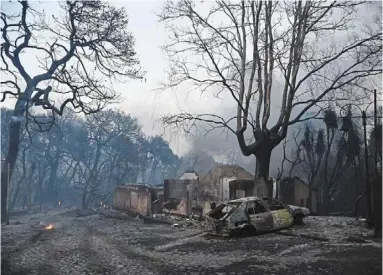  ?? — ap ?? Aftermath: small flames are seen still burning near the charred remains of a caranda house during a wildfire near Lampiri village, west of Patras, greece.