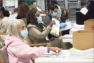  ?? Curtis Compton / Associated Press ?? Election workers check in, sort and signature verify absentee ballots for the state’s U.S. Senate runoff election at the Beauty P. Baldwin Voter Registrati­ons and Elections Building on Tuesday night in Lawrencevi­lle, Ga.