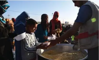  ?? CARL COURT/GETTY IMAGES ?? Iraqi women and children line up for food in Debaga refugee camp, near Mosul, on Saturday.