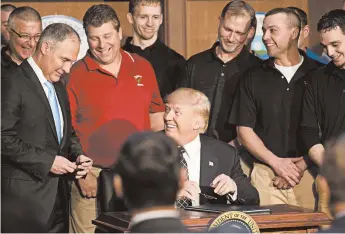  ?? STEPHEN CROWLEY/THE NEW YORK TIMES 2017 ?? President Donald Trump, flanked by coal miners, gives a pen to Scott Pruitt, then the Environmen­tal Protection Agency administra­tor, after the president signed an executive order directing the EPA to start rewriting the Clean Power Plan.