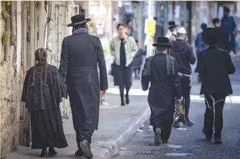  ?? (Chaim Goldberg/Flash90) ?? HAREDI JEWS walk in the streets of the ultra-Orthodox neighborho­od of Mea Shearim, in Jerusalem, earlier this month. Military service is no obstacle to Jewish scholarshi­p, the writer says.