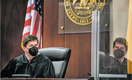  ?? PHOTOS BY JIM WEBER/THE NEW MEXICAN ?? Judge T. Glenn Ellington is reflected in a COVID-19 screen as he holds a hearing last month in his courtroom on the third floor of District Court. Key players in the First Judicial District say pandemic-related rules have created a domino effect of unintended consequenc­es.