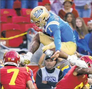  ?? Allen J. Schaben Los Angeles Times ?? DORIAN THOMPSON-ROBINSON hurdles USC cornerback Isaac Taylor-Stuart, right, and beats safety Chase Williams (7) to the end zone in the final quarter of UCLA’s 62-33 win last year, its biggest in the rivalry.