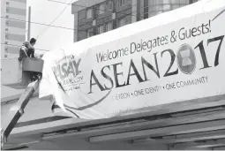  ??  ?? ‘ONE COMMUNITY’ – Workers lay out a banner of the 50th Associatio­n of Southeast Asian Nations (ASEAN) Summit on a flyover along Buendia Avenue to welcome officials, delegates, and guests to the event, which started yesterday. (Jay Ganzon)