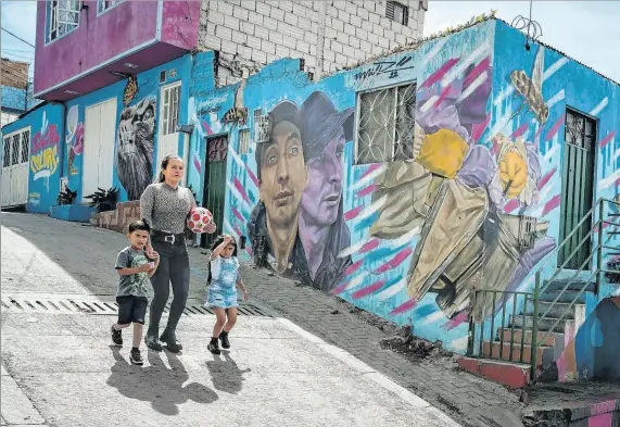  ?? ?? Galeria. Habitantes de Ciudad Bolívar caminan por la calle del color, en Bogotá, y aprecian los murales donde se cuentan las historias a través del arte.