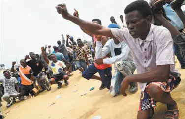  ?? Pius Utomi Ekpei / AFP via Getty Images ?? Protesters against police brutality raise hands in salute to the national anthem in Magboro city, Nigeria.