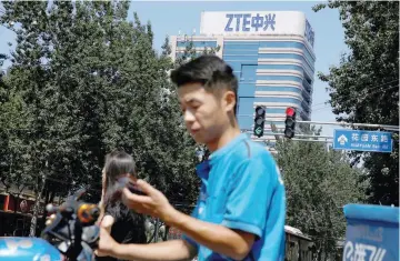  ?? — Reuters ?? A delivery man uses a phone near a building of China’s ZTE Corp in Beijing, China.