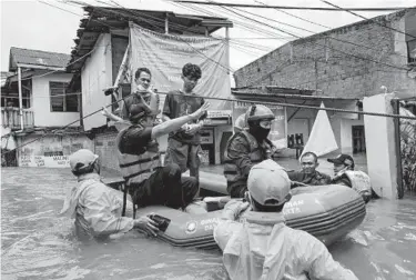  ?? ED WRAY/GETTY ?? Rescue workers help evacuate people from a flooded neighborho­od Saturday in Jakarta, Indonesia. Severe flooding in numerous areas of the Indonesian capital city forced more than 1,300 people to be evacuated from their homes. The country’s weather service warned that conditions could worsen in the coming week.