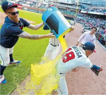  ?? AP PHOTOS/CURTIS COMPTON ?? The Atlanta Braves’ Mike Foltynewic­z (left) and Matt Joyce give Rafael Ortega, right, a cooler bath after Sunday’s 5-3 victory over the Los Angeles Dodgers in Atlanta. Ortega hit a grand slam in the sixth inning.