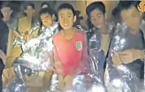  ??  ?? The trapped boys in survival blankets, in a video taken by navy Seals, above. Their relatives, top left, wait to hear news of how they can be brought to the surface in safety