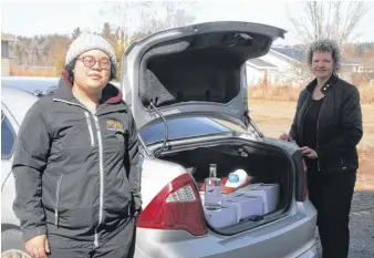  ?? LYNN CURWIN/TRURO NEWS ?? Amber Maclean Hawes, left, picked up some hand sanitizer being donated to the Union of Nova Scotia Mi’kmaq by Raging Crow Distillery. Helping load the car was distillery president Jill Lindquist.