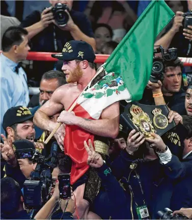  ?? Ethan Miller / Getty Images ?? El boxeador mexicano Saúl ‘Canelo’ Álvarez celebra en el medio del cuadriláte­ro tras consagrars­e el sábado como nuevo campeón mundial de peso mediano en el T-Mobile Arena de Las Vegas, Nevada.