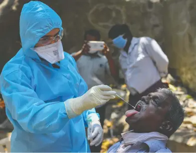  ?? INDRANIL MUKHERJEE / AFP VIA GETTY IMAGES ?? A doctor in Mumbai takes a swab sample on Thursday at a COVID-19 testing drive inside the Dharavi slums during a
government-imposed nationwide lockdown as a preventive measure against the spread of the coronaviru­s.