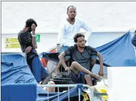  ?? AP PHOTO ?? Migrants sit on the deck of the Italian Coast Guard ship Diciotti at the Catania harbor, Italy, Thursday.