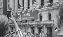  ?? Drew Angerer / Getty Images ?? Tourists take photos near the New York Stock Exchange. The bull market for U.S. stocks began in March 2009.