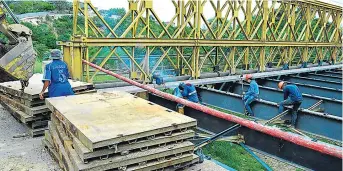  ?? ?? Obreros intensific­an trabajos previo a la colocación de las planchas metálicas sobre el puente en Picoazá.