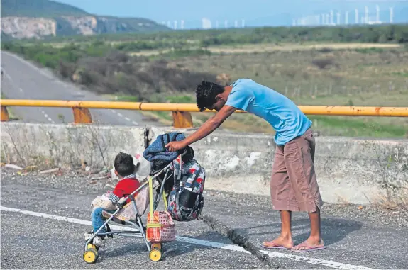  ?? Picture: AP. ?? A man and child on a Mexican highway as a thousands-strong caravan of Central Americans heads toward the US border.