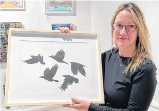  ?? WENDY ELLIOTT ?? Artist Sheri Hancock holds up one of her newest prints being exhibited at the Tides Contempora­ry Art Gallery in Kentville until late May.