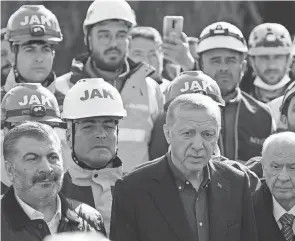  ?? YASIN AKGUL/AFP VIA GETTY IMAGES ?? Turkish President Recep Tayyip Erdogan stands with rescue workers as he visits the hard-hit southeaste­rn province of Hatay Monday. His visit came before a new 6.4-magnitude quake hit the area.