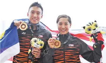  ?? — BERNAMA photo ?? National swimmers Kevin Yeap Soon Choy (left) and Heidi Gan celebrate with their gold medals after winning the Men's and Women's 10km Open Water swimming event at the 29th Kuala Lumpur SEA Games yesterday.
